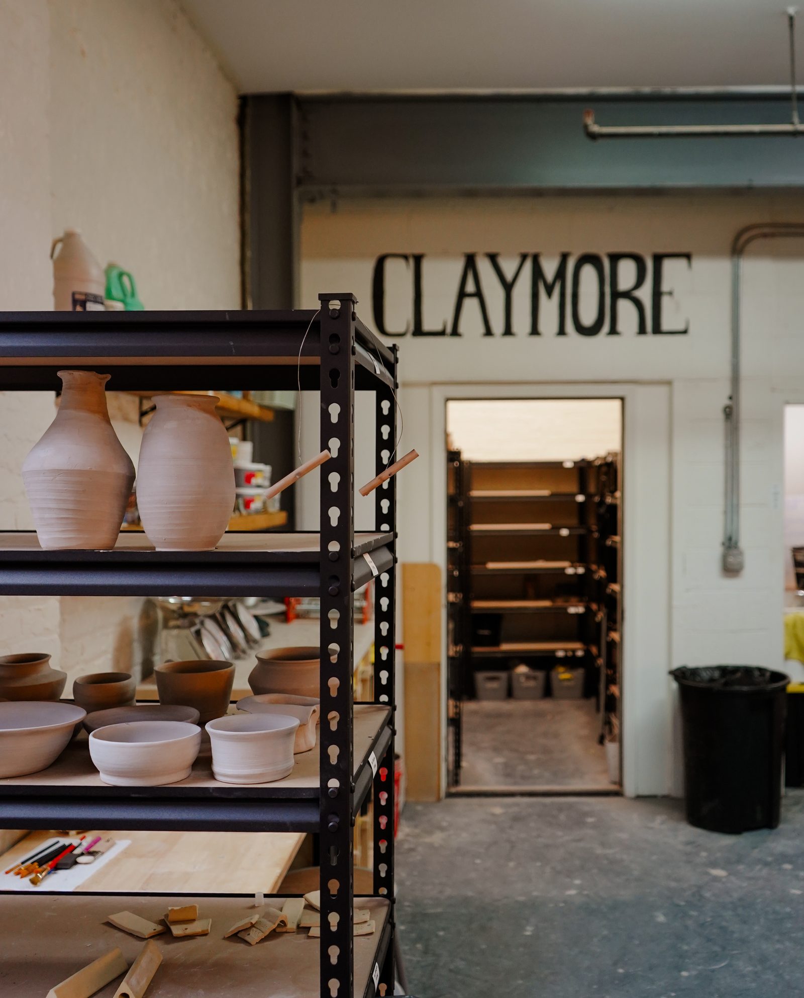 The hand-painted Claymore sign on the studio wall, with member shelves beyond
