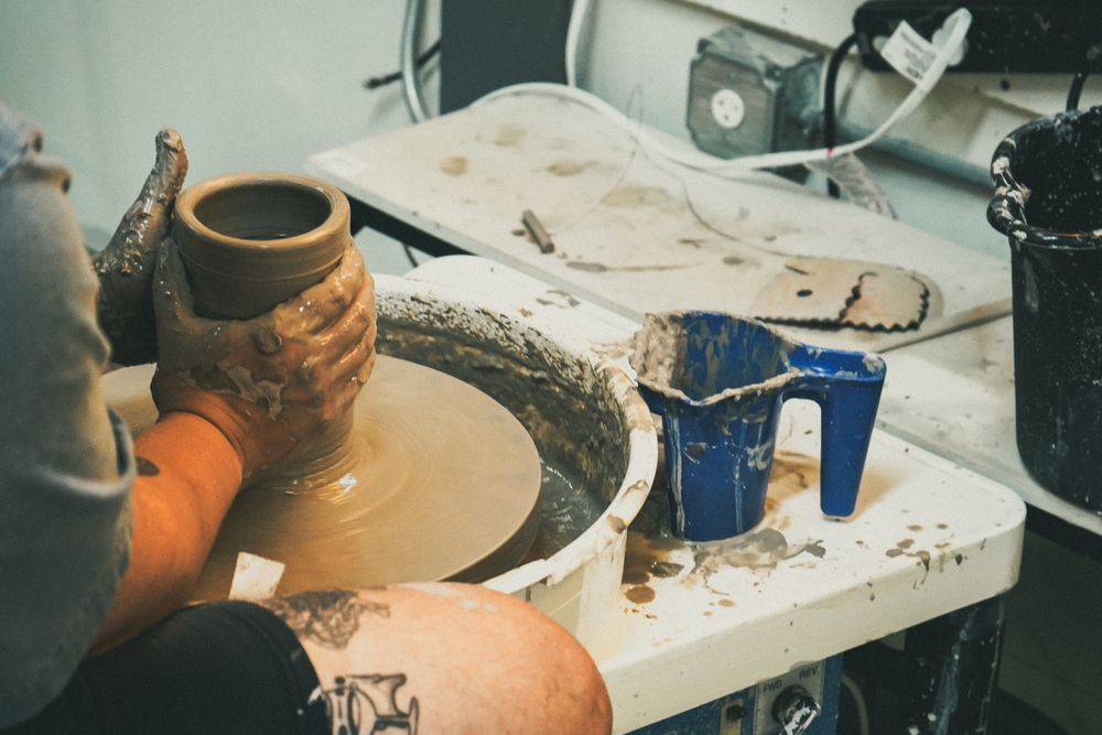 Hands working wet clay on the wheel