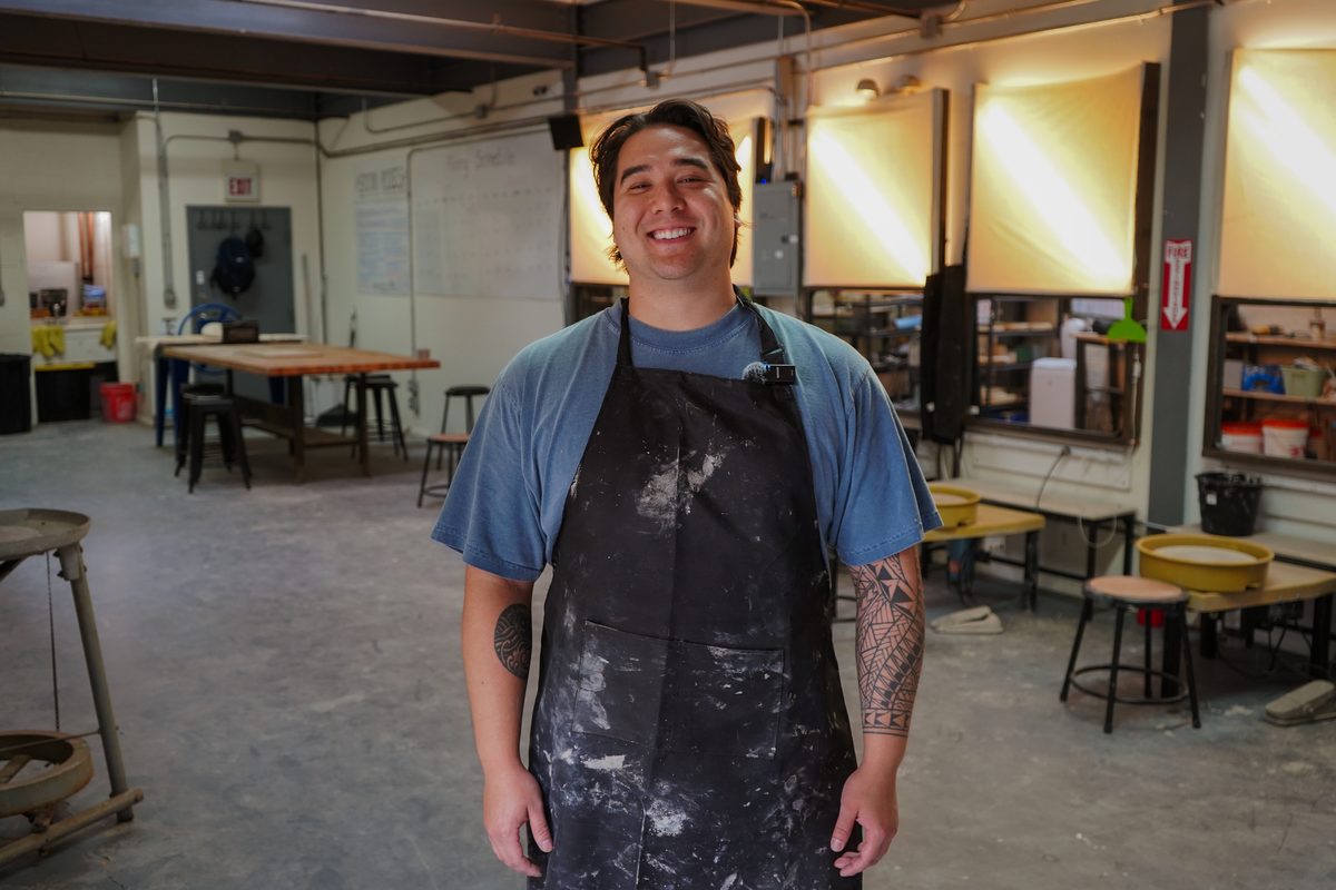 A Claymore member in a clay-splattered apron on the studio floor